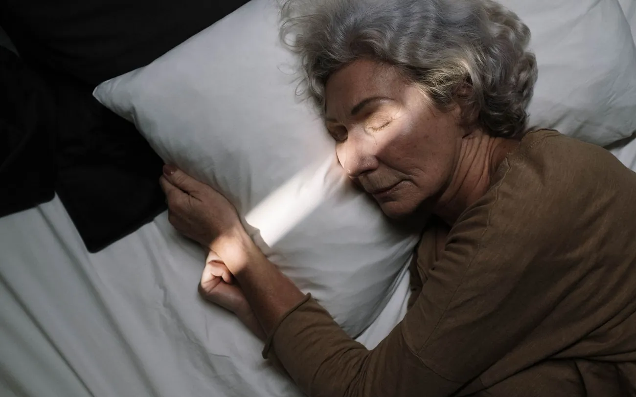 Woman with gray hair resting peacefully in bed despite hot flashes